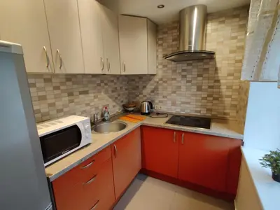 a small kitchen with red cabinets and a sink at Jaukus butukas in Druskininkai