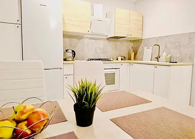 a kitchen with white cabinets and a bowl of fruit on a table at M&M Apartment I SELF CHECK-IN near Panevezys in Velžys