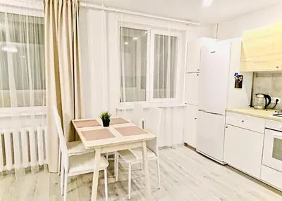 a white kitchen with a small table and chairs at M&M Apartment I SELF CHECK-IN near Panevezys in Velžys