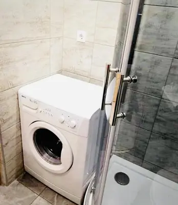 a washing machine in a bathroom with a shower at M&M Apartment I SELF CHECK-IN near Panevezys in Velžys