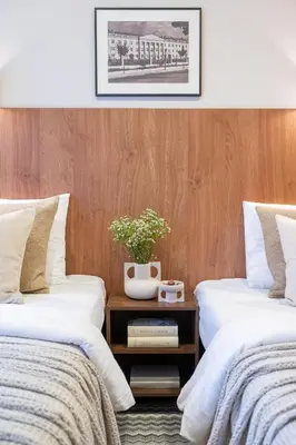 two beds with white sheets and a plant on a table at Nėris Inn Terraces in Vilnius