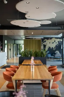 a large wooden table in a lobby with orange chairs at Park Inn by Radisson Vilnius Airport Hotel & Conference Centre in Vilnius