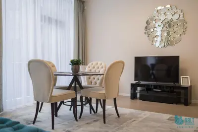 a dining room with a table and chairs and a television at Salt Apartments in Druskininkai