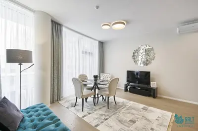 a living room with a table and chairs and a tv at Salt Apartments in Druskininkai