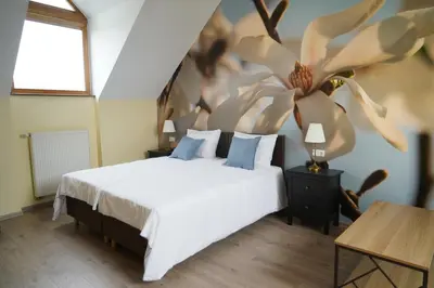 a bedroom with a white bed with a flower on the wall at Timėjas in Ringaudai