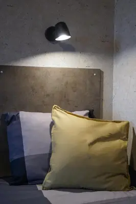a bed with a yellow pillow and a lamp at Timėjas in Ringaudai