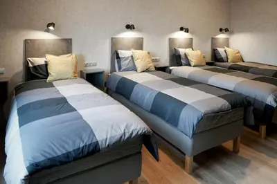 three beds in a room with blue and white sheets at Timėjas in Ringaudai