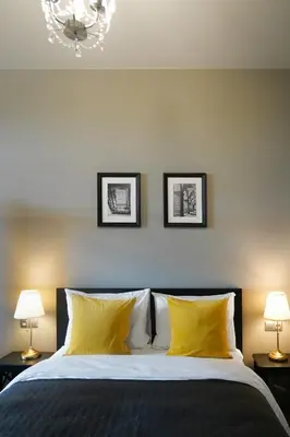 a bedroom with a bed with yellow pillows and two lamps at Timėjas in Ringaudai
