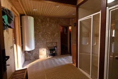 a bathroom with a walk in shower next to a stone wall at Sodyba 