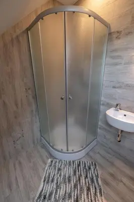 a shower in a bathroom with a sink and a rug at Sodyba 