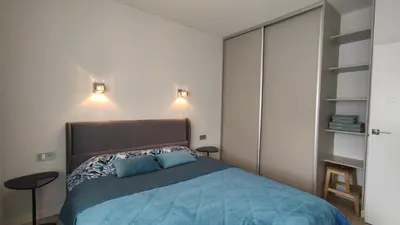 a bedroom with a bed with blue sheets and lights at NEW J&R Apartment near Girstutis, Free private parking & Self Check-In in Kaunas