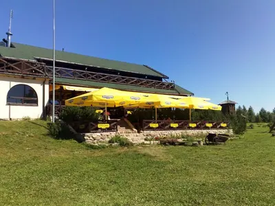 a building with yellow umbrellas in a field at Kurėnų Užeigos Svečių Namai in Kurėnai