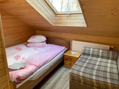 a small attic bedroom with a bed and a window at Kurėnų Užeigos Svečių Namai in Kurėnai