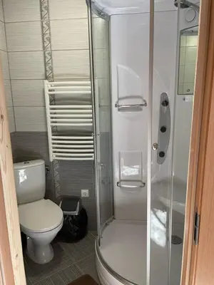 a bathroom with a toilet and a glass shower at Kurėnų Užeigos Svečių Namai in Kurėnai