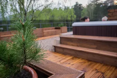 a wooden deck with a bench and a tree at Goda Hotel & Spa in Druskininkai