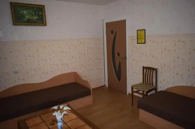 a room with two beds and a chair and a door at Chernobyl type rooms in a block flat house in Šiauliai
