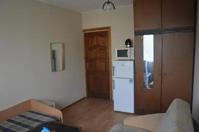 a small kitchen with a white refrigerator and a door at Chernobyl type rooms in a block flat house in Šiauliai