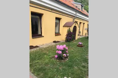 a house with pink flowers in the yard at Editas apartament in Kaunas