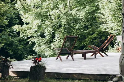 two wooden chairs and a bench on a patio at VasaRojaus Jurta in Birštonas