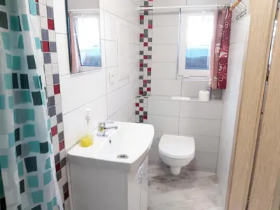a white bathroom with a toilet and a sink at Studio by the Lake Kaunas in Kaunas