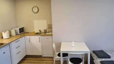 a kitchen with a table and chairs and a clock on the wall at Bitenu Studio in Vilnius