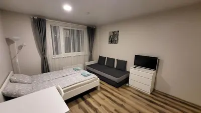 a bedroom with a bed and a chair and a television at Bitenu Studio in Vilnius