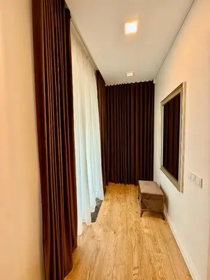 a living room with a wooden floor and curtains at Varpo 17 in Šiauliai