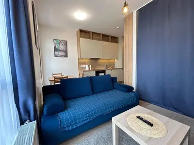 a living room with a blue couch and a table at Your Home - Stylish Studio Apartment in Center, with Balcony & Self Check-in in Vilnius