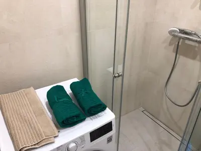 a bathroom with a shower with green towels on a washing machine at Your Home - Stylish Studio Apartment in Center, with Balcony & Self Check-in in Vilnius