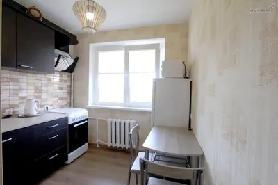a small kitchen with a table and a refrigerator at Tilžės Apartment in Šiauliai