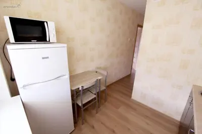a small kitchen with a refrigerator and a table at Tilžės Apartment in Šiauliai
