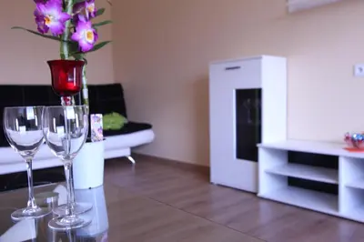 a living room with two wine glasses and a vase with flowers at Tilžės Apartment in Šiauliai