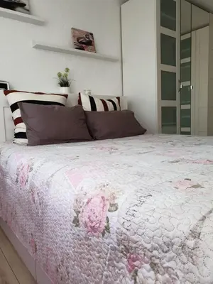 a bedroom with a large bed with pink flowers on it at Marijampolės jaukūs apartamentai in Marijampolė