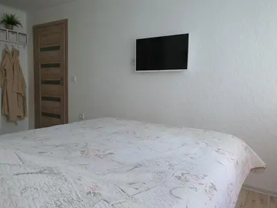 a bedroom with a bed with a tv on the wall at Marijampolės jaukūs apartamentai in Marijampolė