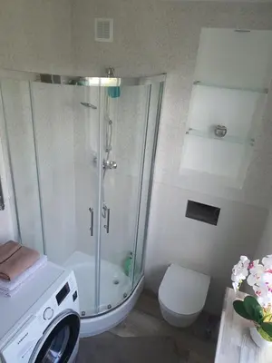 a bathroom with a shower and a washing machine at Marijampolės jaukūs apartamentai in Marijampolė