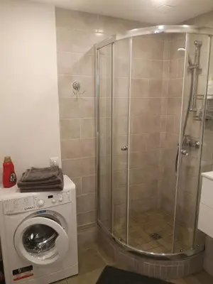 a shower stall in a bathroom with a washing machine at Parko apartamentai in Panevėžys
