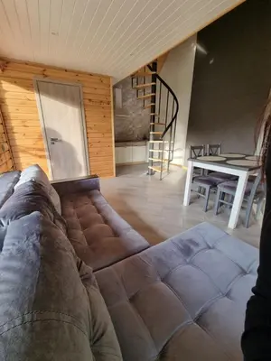 a couch in a living room with a table and stairs at Sodyba 