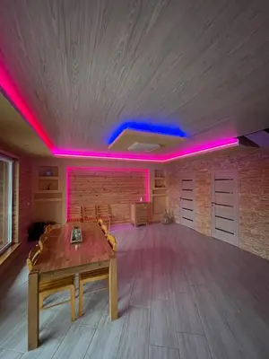 a room with a table in a room with pink lights at Sodyba 