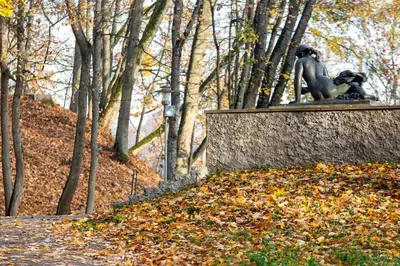 a statue of a man sitting on a wall next to trees at Relax apartments near Egle in Druskininkai