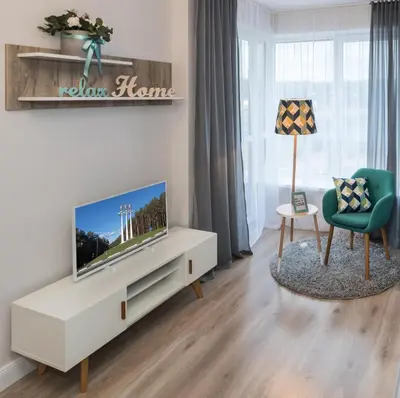 a living room with a television and a chair at Relax apartments near Egle in Druskininkai
