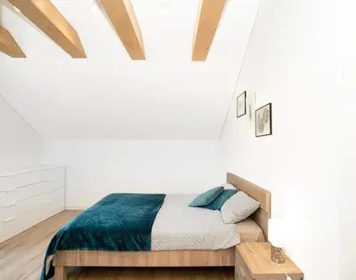 a bedroom with white walls and a bed with a blue blanket at Kaunas Castle Apartments - Studio in Kaunas
