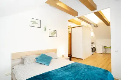 a white bedroom with a bed with blue pillows at Kaunas Castle Apartments - Studio in Kaunas