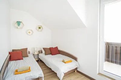 two beds in a room with a window at Kaunas Castle Apartments - 2 Bedroom Flat in Kaunas