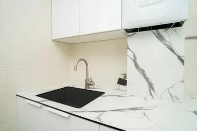a white kitchen with a sink and a counter at Kaunas Castle Apartments - 2 Bedroom Flat in Kaunas