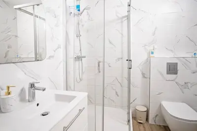 a white bathroom with a shower and a sink at Kaunas Castle Apartments - 2 Bedroom Flat in Kaunas