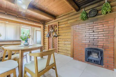 a living room with a brick fireplace and a table and chairs at Bedugnės pirtelė - Cosy Sauna House in Vilnius