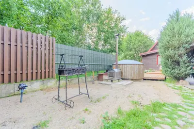a barbecue grill in a yard with a fence at Bedugnės pirtelė - Cosy Sauna House in Vilnius