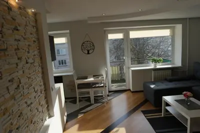 a living room with a couch and a brick wall at Dange apartment in Šiauliai