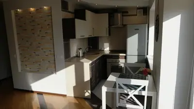 a kitchen with white cabinets and a brick wall at Dange apartment in Šiauliai