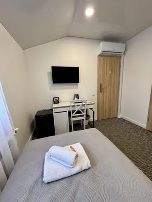 a room with a bed with a desk and a television at Grey apartments 
